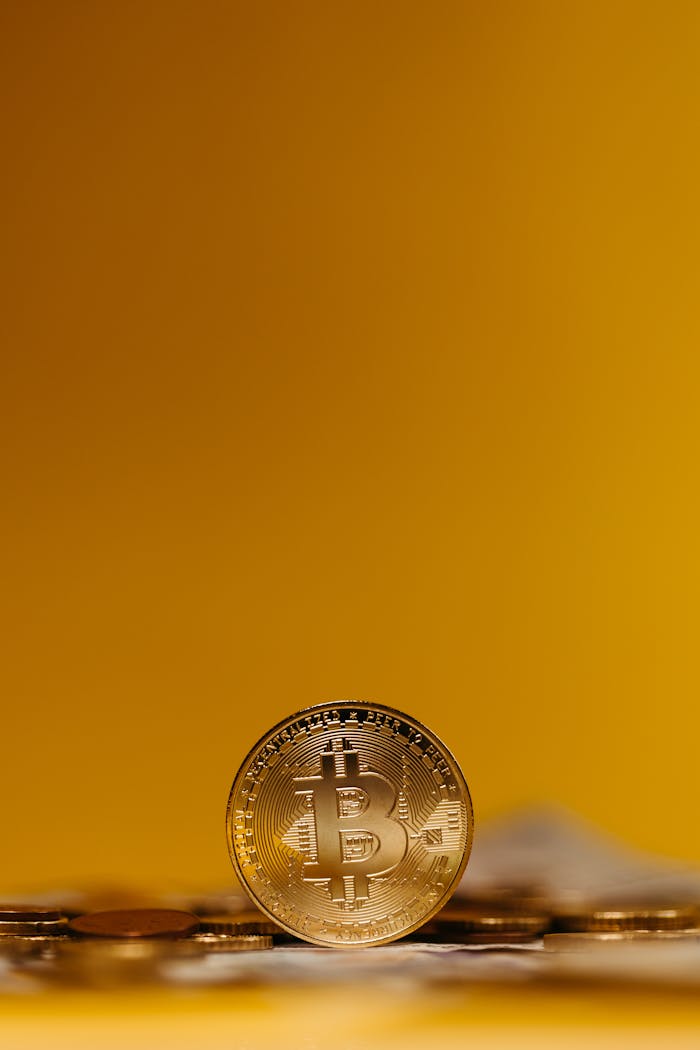 Services Close-up of a Bitcoin coin standing upright on a blurred yellow background, symbolizing digital finance.